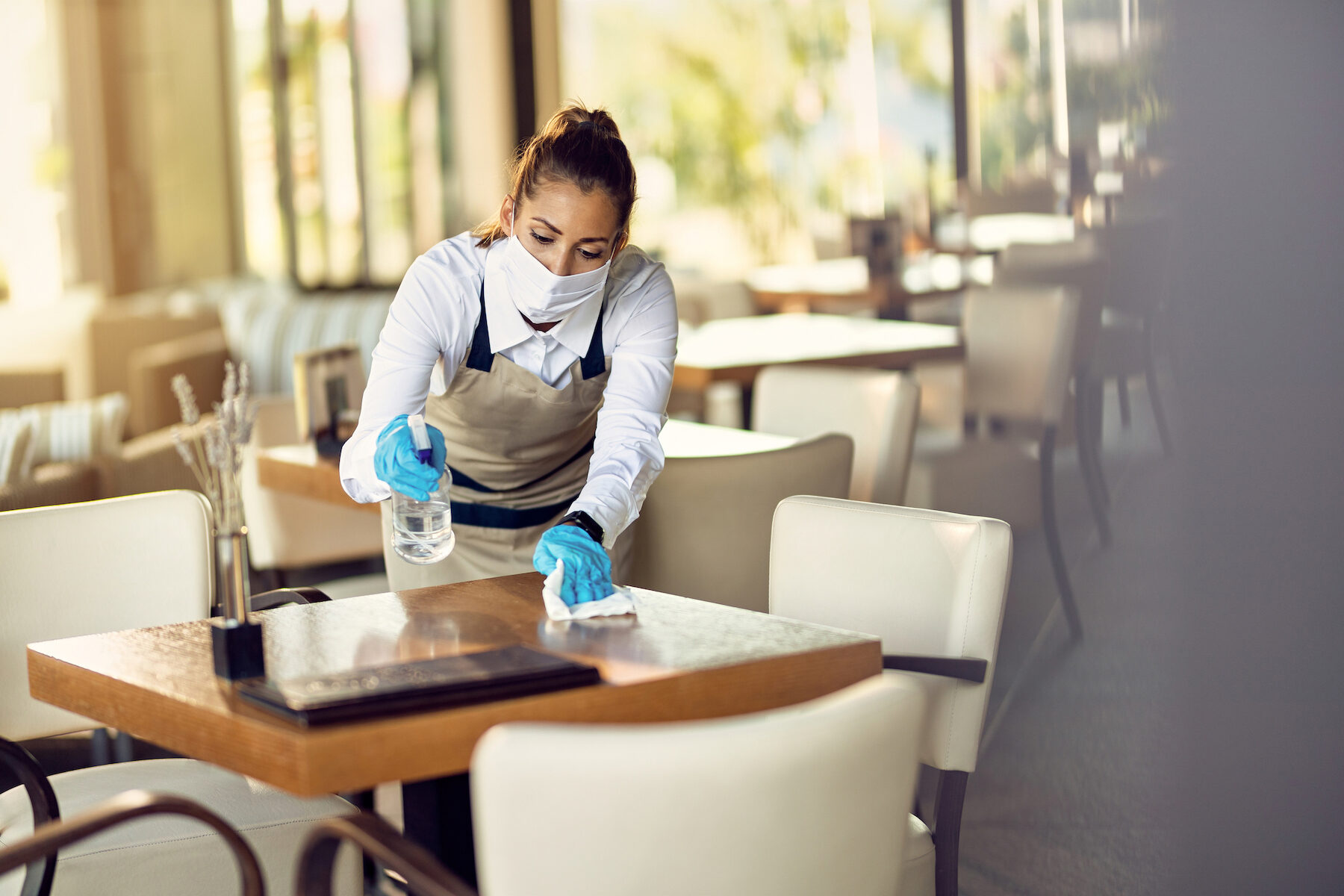 Camarera mascarilla desinfectando mesas restaurante debido pandemia coronavirus